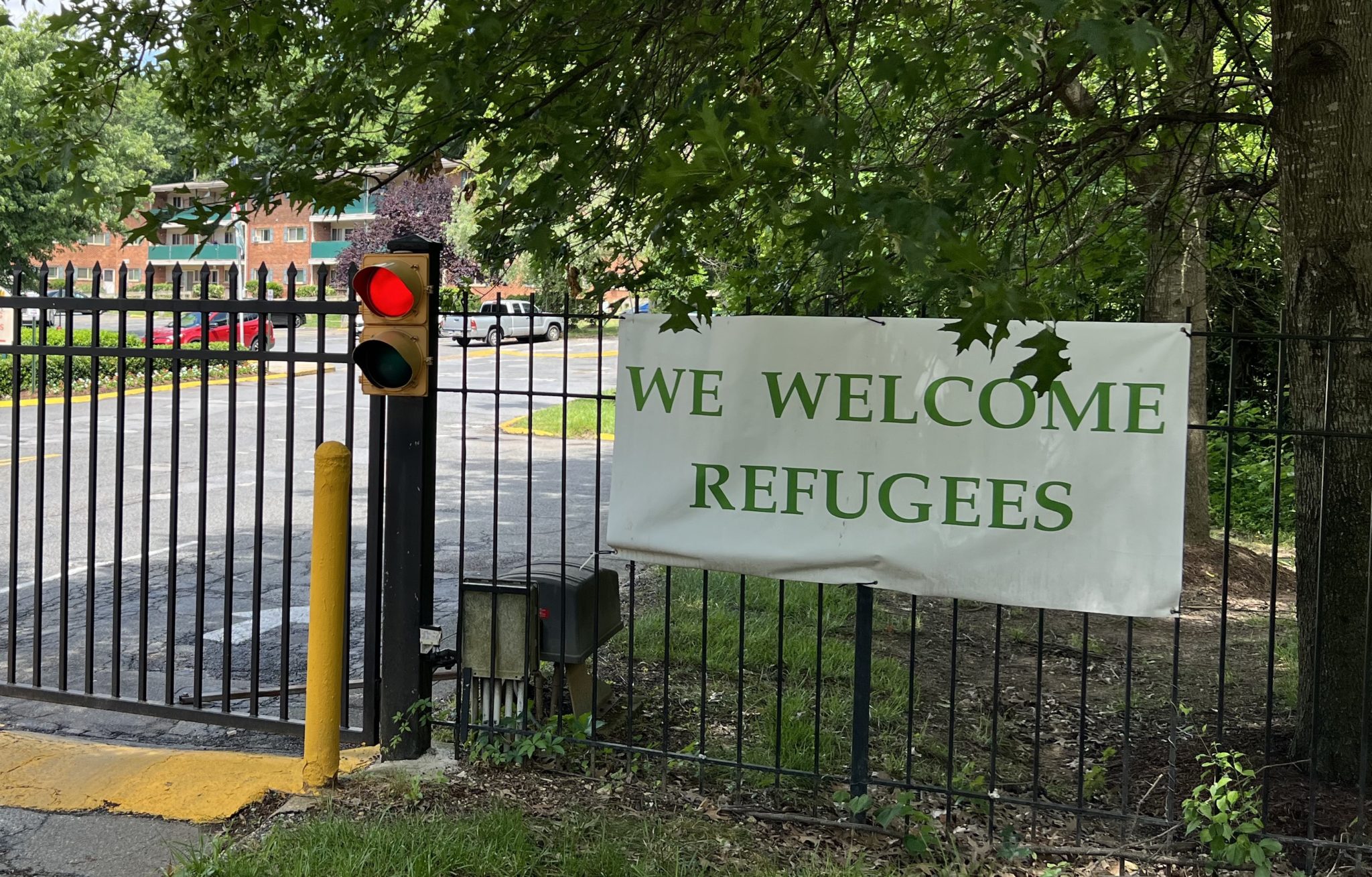 Photo of a fence with a sign that reads "We Welcome Refugees"